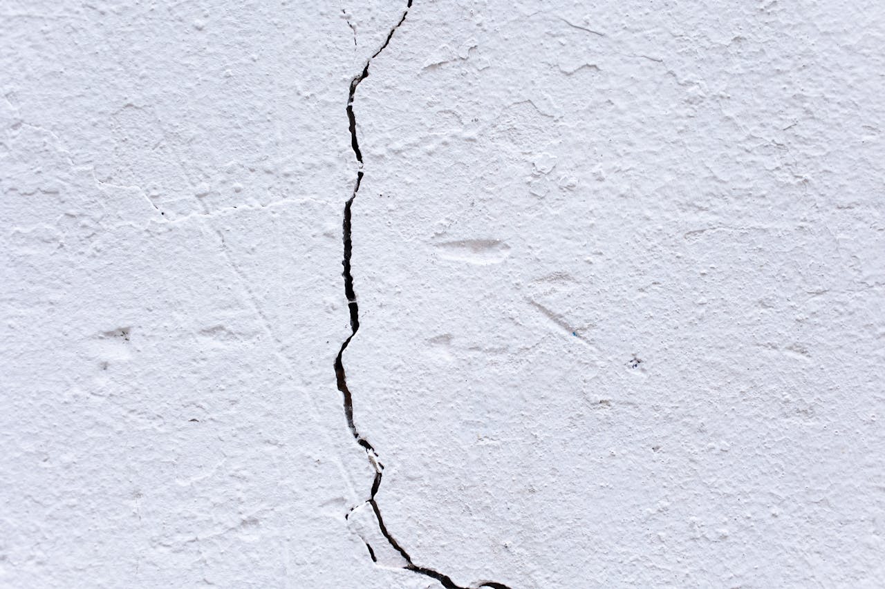 Close-up of a cracked white textured wall highlighting its worn and aged character.